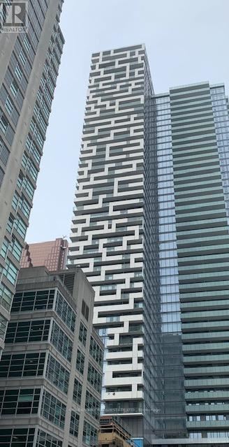 Toronto (Church-Yonge Corridor) condo for rent - A tall building with a patterned facade stands between two other buildings.