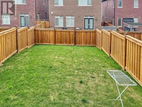 Oakville (Go Glenorchy) townhouse for rent - A backyard with a wooden fence and a green lawn.