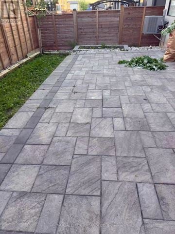 London North (North B) house for rent - A grey paved walkway leads to a wooden fence.