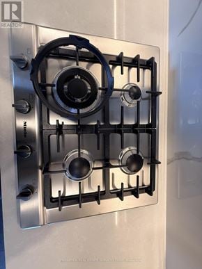 Toronto (Bayview Village) condo for rent - A stainless steel gas stove with four burners and a blue tape around the knobs.