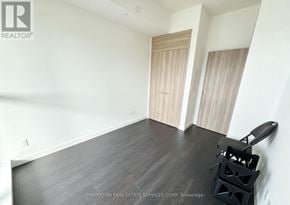 Toronto (Bayview Village) condo for rent - A room with a black chair and wooden floors.