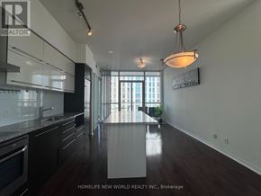 Toronto (Church-Yonge Corridor) condo for rent - A modern kitchen with dark wood floors and white walls.