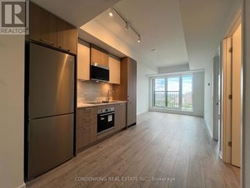 Toronto (Regent Park) condo for rent - A modern kitchen with wooden cabinets and a stainless steel refrigerator.