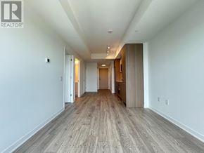 Toronto (Regent Park) condo for rent - A long, empty hallway with wood flooring and white walls.
