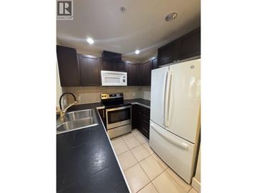Vancouver apartment for rent - A kitchen with a white fridge and black countertops.
