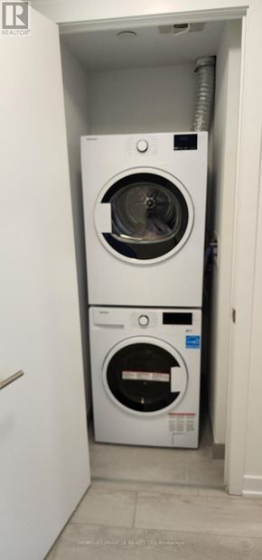 Toronto (Church-Yonge Corridor) condo for rent - A white washing machine is installed in a small, white-walled laundry room.