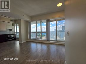 Toronto (Waterfront Communities) condo for rent - A spacious room with wooden floors and large windows overlooking a cityscape.