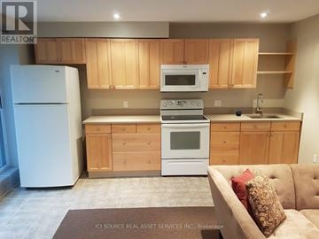 Toronto (Ionview) duplex for rent - A kitchen with wooden cabinets and a white fridge.