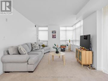 Toronto (Scarborough Village) condo for rent - A living room with a grey couch and a wooden coffee table.