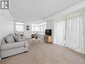 Toronto (Scarborough Village) condo for rent - A living room with a grey couch, a wooden coffee table, and a flat screen TV.
