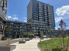 Burlington (Appleby) condo for rent - A modern apartment complex with a parking lot in front.