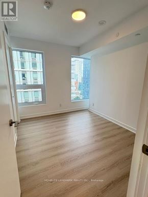 Toronto (Church-Yonge Corridor) condo for rent - A room with wooden flooring and a window overlooking a cityscape.