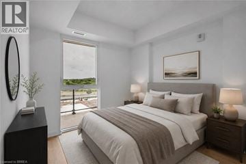 Brantford condo for rent - A bedroom with a large bed, a window with a view, and a nightstand with a lamp.