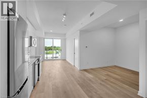 Brantford condo for rent - A spacious, empty room with wooden floors and white walls.