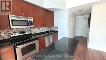 Toronto (Mimico) condo for rent - A kitchen with wooden cabinets and a black countertop.