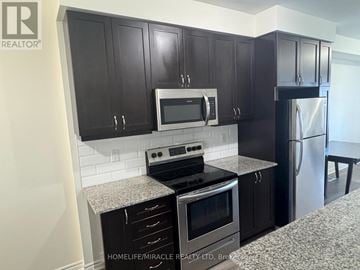 Pickering townhouse for rent - A kitchen with black cabinets and stainless steel appliances.