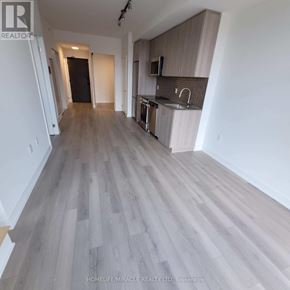 Oakville (Jm Joshua Meadows) condo for rent - A spacious room with wooden flooring and a kitchen area with a sink and stove.