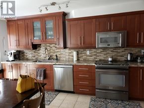 Mississauga (Churchill Meadows) apartment for rent - A kitchen with brown cabinets and a stone backsplash.