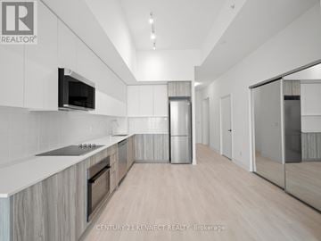 Oakville (Ro River Oaks) condo for rent - A modern kitchen with wooden cabinets and a stainless steel refrigerator.