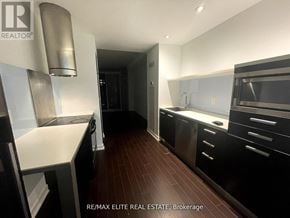 Toronto (Waterfront Communities) condo for rent - A modern kitchen with dark wood floors and stainless steel appliances.