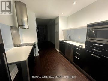 Toronto (Waterfront Communities) condo for rent - A modern kitchen with dark wood floors and stainless steel appliances.