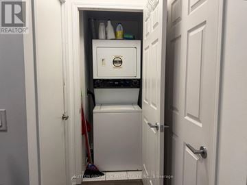 Toronto (Downsview-Roding-Cfb) condo for rent - A small white refrigerator is tucked into a narrow space under a door.