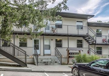 Nashville apartment for rent - A black car is parked on the street in front of a two-story building with a balcony.