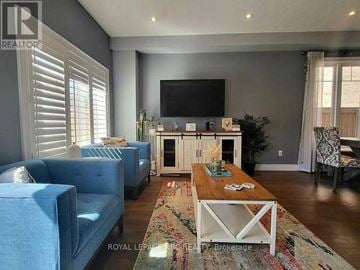 Hamilton (Lakeshore) townhouse for rent - A living room with a blue couch, a wooden coffee table, and a television on the wall.