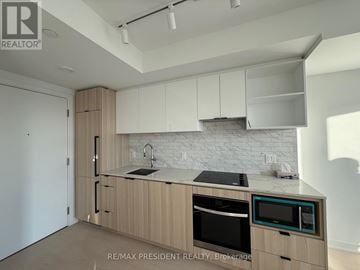 Toronto (Church-Yonge Corridor) condo for rent - A kitchen with wooden cabinets and a white brick backsplash.