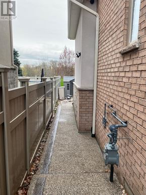 Oakville (Br Bronte) apartment for rent - A narrow alley with a brick wall on one side and a wooden fence on the other.