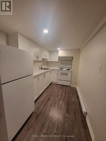 St. Catharines (Old Glenridge) apartment for rent - A kitchen with white cabinets and a wooden floor.
