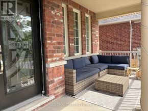 Brampton (Bram West) apartment for rent - A blue couch is on a patio with a brick wall.