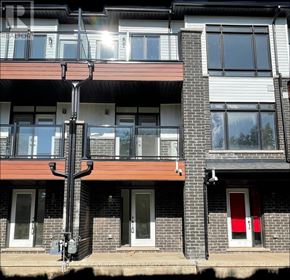 St. Catharines (Glendale/Glenridge) townhouse for rent - A building with a red door and a balcony with a black railing.