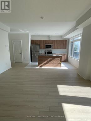 St. Catharines (Glendale/Glenridge) townhouse for rent - A spacious kitchen with wooden cabinets and a microwave.