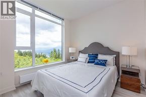 Burnaby apartment for rent - A bedroom with a large bed and a window overlooking a green landscape.