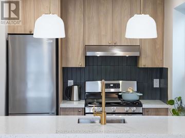 Toronto (South Riverdale) apartment for rent - A modern kitchen with a stainless steel refrigerator and a stove top oven.
