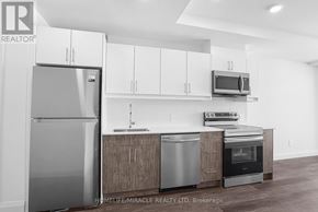 Kitchener condo for rent - A modern kitchen with a refrigerator, microwave, oven, and cabinets.