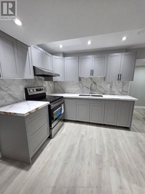 Whitchurch-Stouffville (Stouffville) apartment for rent - A modern kitchen with a marble backsplash and grey cabinets.