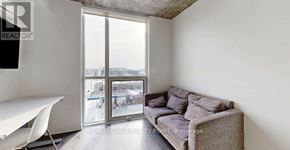 Oshawa (Samac) condo for rent - A living room with a grey couch and a white chair.