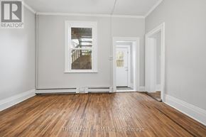 London South (South F) fourplex for rent - A room with wooden floors and white walls, with a picture frame on the wall.