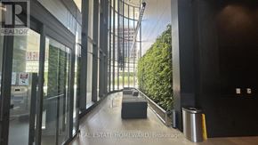 Toronto (Waterfront Communities) condo for rent - A hallway with glass doors leading to a balcony with trees.