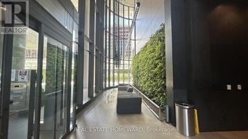 Toronto (Waterfront Communities) condo for rent - A hallway with glass doors leading to a balcony with trees.