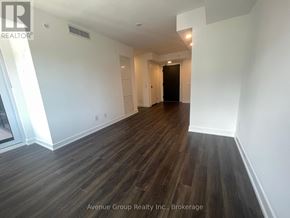 Toronto (North St. James Town) condo for rent - A spacious room with wooden flooring and white walls.