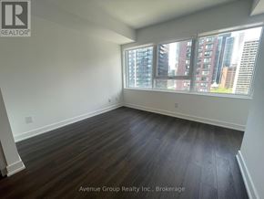 Toronto (North St. James Town) condo for rent - A large empty room with wooden floors and a window overlooking a cityscape.