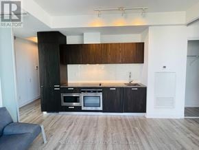 Toronto (Church-Yonge Corridor) condo for rent - A modern kitchen with dark wood cabinets and stainless steel appliances.