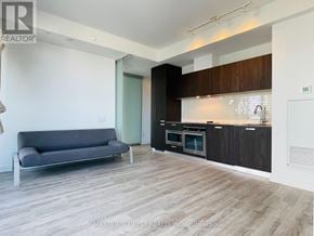Toronto (Church-Yonge Corridor) condo for rent - A modern kitchen with dark wood cabinets and a grey sofa.