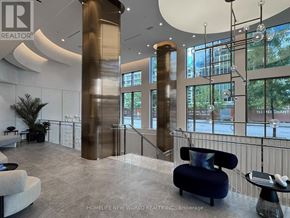 Toronto (Waterfront Communities) condo for rent - A modern office lobby with a blue sofa and a glass chandelier.