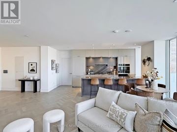 Toronto (Waterfront Communities) condo for rent - A modern living room with a grey couch and a kitchen in the background.