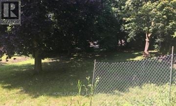 Newmarket (Huron Heights-Leslie Valley) apartment for rent - A chain link fence separates a grassy area from a wooded area.