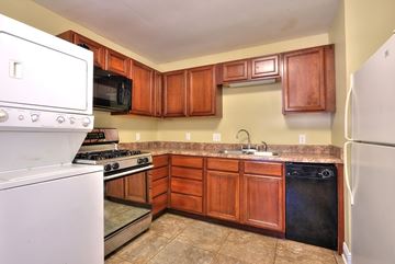 Slidell apartment for rent - A kitchen with wooden cabinets and a white refrigerator.